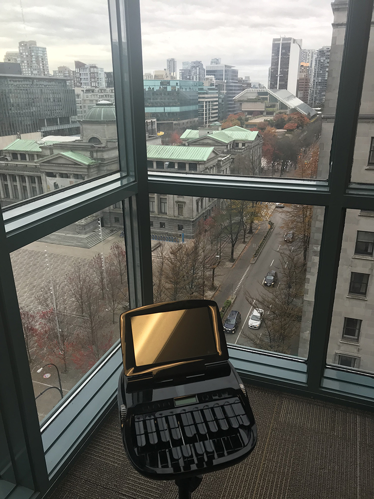 BCSRA court reporter's stenograph machine in front of windows overlooking the Downtown Vancouver courthouse