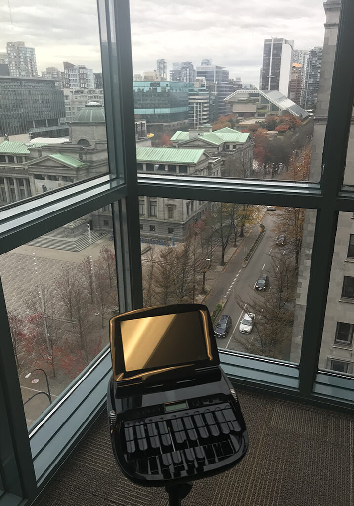 BCSRA court reporter's stenograph machine in front of windows overlooking the Downtown Vancouver courthouse